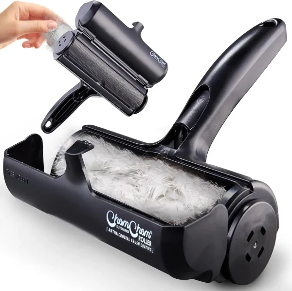 A sleek black ChomChom Roller held against a charcoal grey sofa covered in white cat hair.